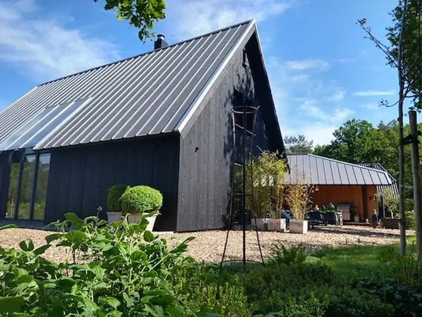 Schuurwoning met een donker dak in zinklook en een zwarte houten gevel