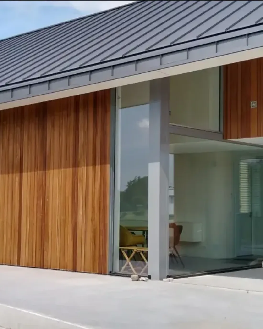 Woonhuis met houten gevelbekleding en zinklook in donkere staande fels