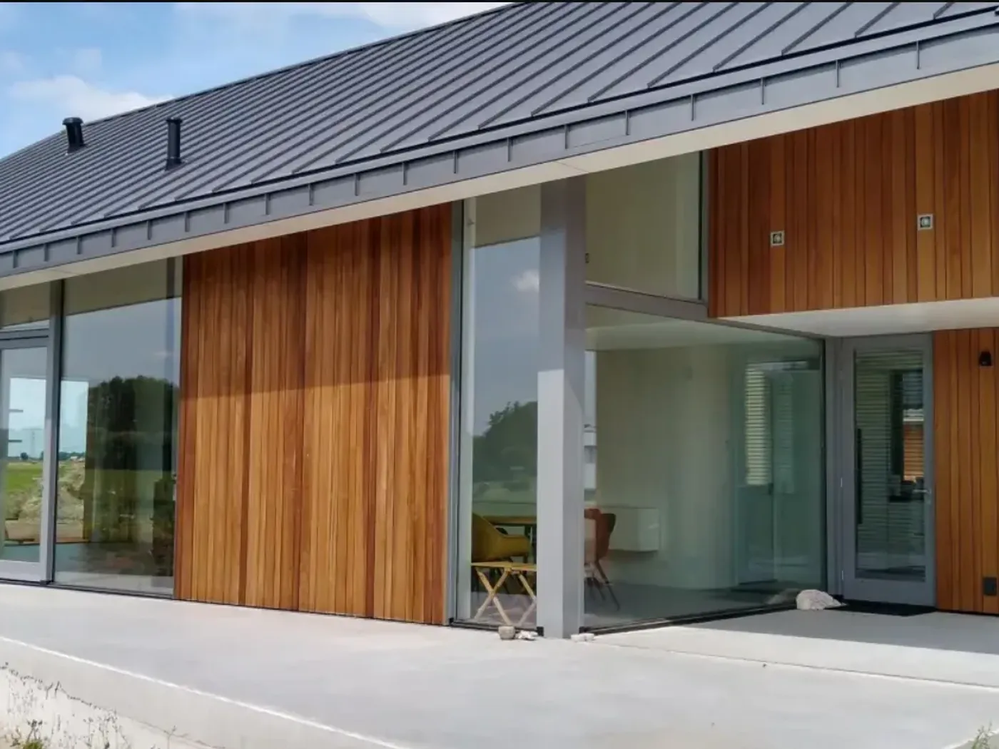 Woonhuis met houten gevelbekleding en een dak in zinklook, donkere staande fels